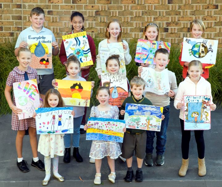 A group of 13 school children pose with their handmade posters. 