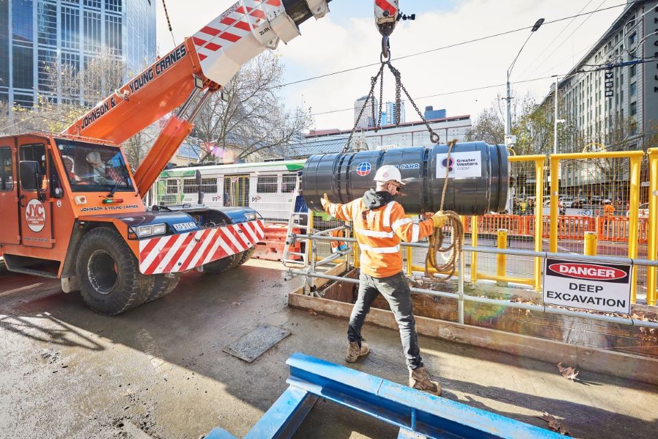 The TBM is lowered into the ground by a worker and crane. 